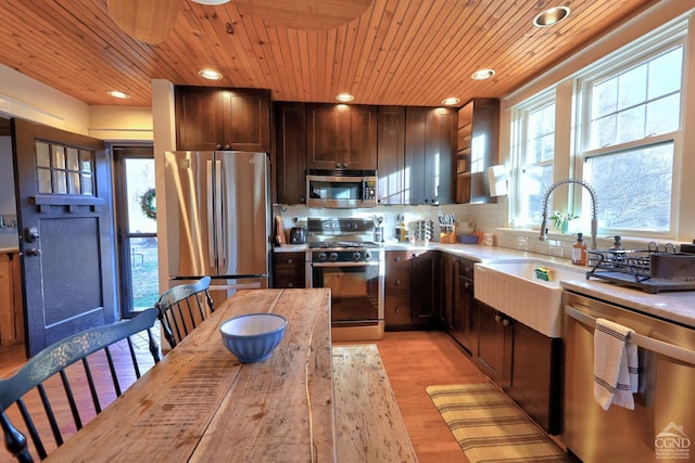 kitchen featuring tasteful backsplash, light wood-type flooring, stainless steel appliances, and wooden ceiling