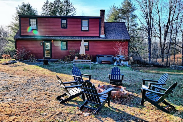 back of property with a hot tub and a fire pit