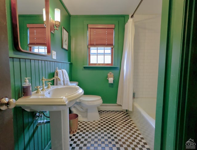 bathroom featuring shower / bath combo with shower curtain, a healthy amount of sunlight, a baseboard radiator, and toilet