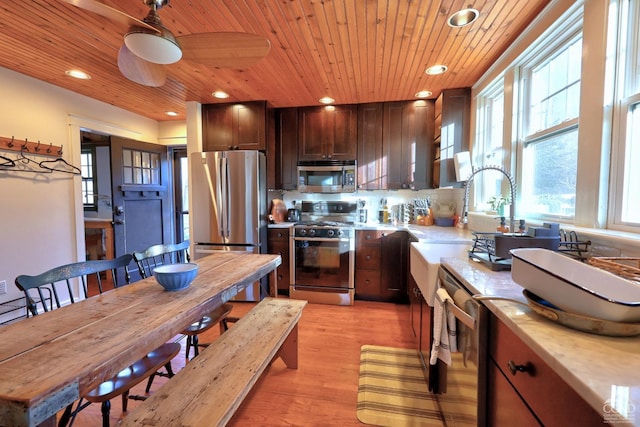 kitchen with ceiling fan, wooden ceiling, stainless steel appliances, decorative backsplash, and light wood-type flooring