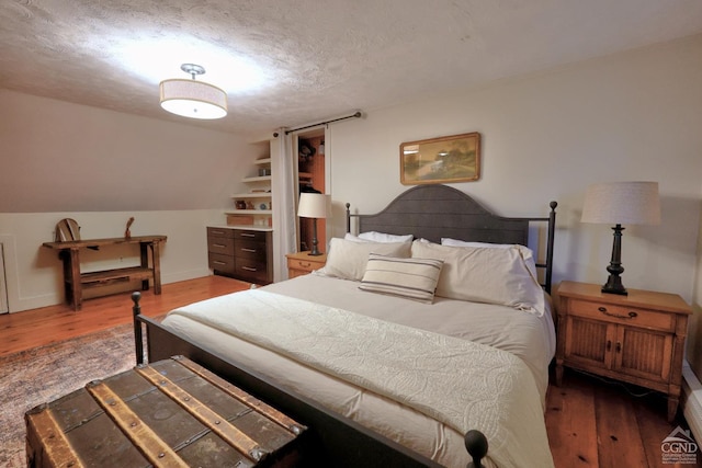 bedroom with lofted ceiling, dark hardwood / wood-style flooring, and a textured ceiling