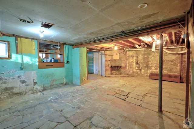 basement featuring radiator heating unit and a fireplace