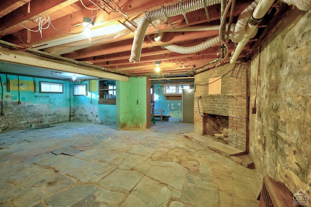 basement featuring plenty of natural light and a brick fireplace