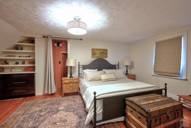 bedroom featuring a textured ceiling and dark hardwood / wood-style flooring