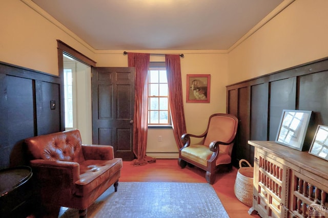 living area featuring ornamental molding, a baseboard radiator, and wood-type flooring