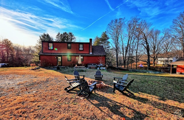 back of property featuring a fire pit and a lawn