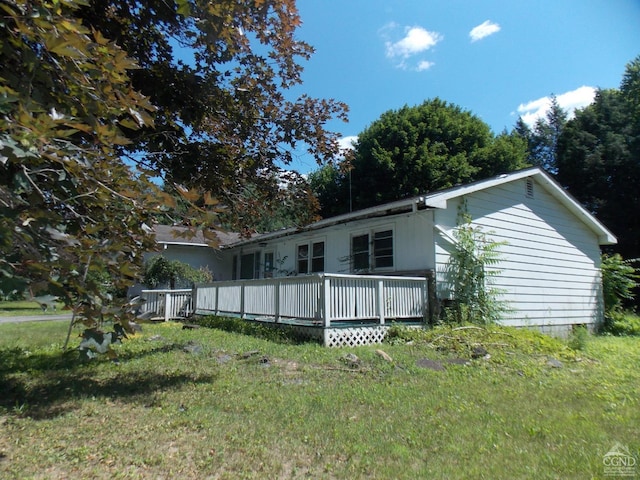 rear view of property with a wooden deck and a yard