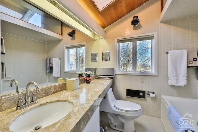 bathroom featuring a wealth of natural light, lofted ceiling with skylight, and tile walls