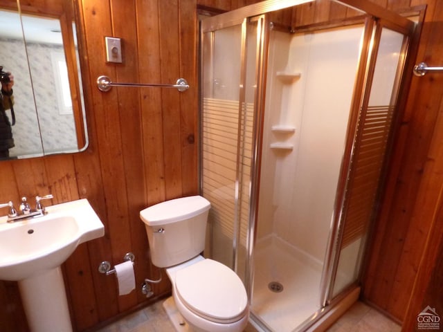 bathroom featuring tile patterned flooring, toilet, wood walls, and an enclosed shower