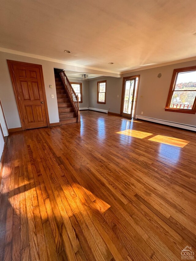 unfurnished living room featuring wood-type flooring, plenty of natural light, and crown molding