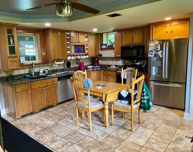 kitchen with sink, decorative backsplash, ceiling fan, dark stone countertops, and appliances with stainless steel finishes