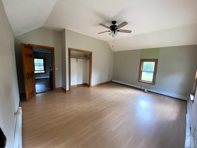 interior space with lofted ceiling, light hardwood / wood-style floors, baseboard heating, and a healthy amount of sunlight