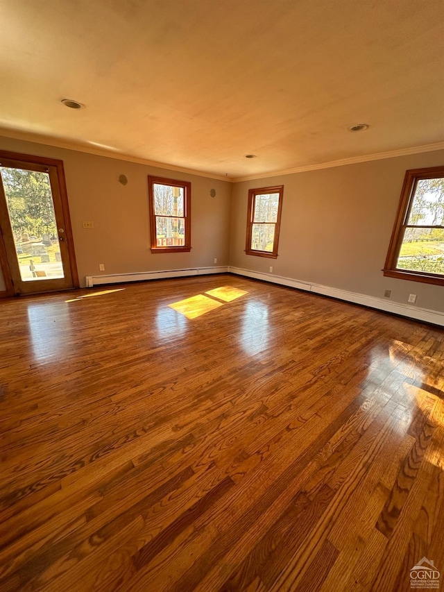 spare room featuring hardwood / wood-style floors, ornamental molding, and a baseboard heating unit