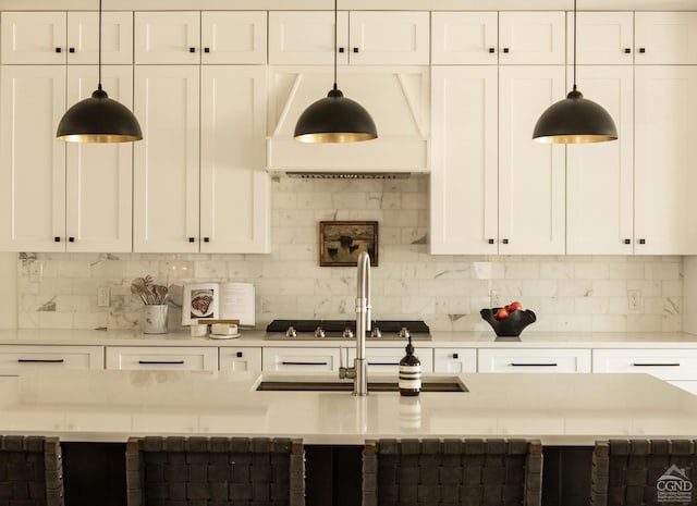 kitchen featuring premium range hood, pendant lighting, white cabinets, and tasteful backsplash