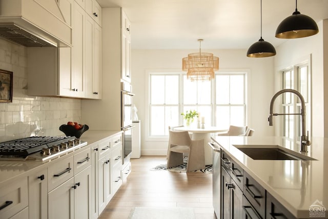 kitchen featuring decorative light fixtures, white cabinetry, appliances with stainless steel finishes, and custom exhaust hood