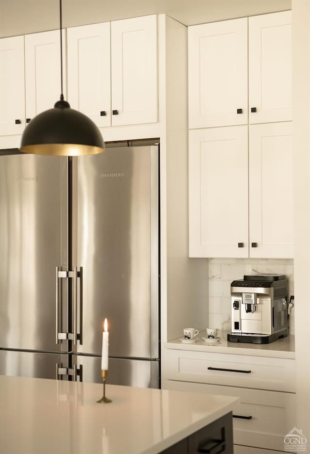 kitchen with backsplash, white cabinetry, and stainless steel refrigerator