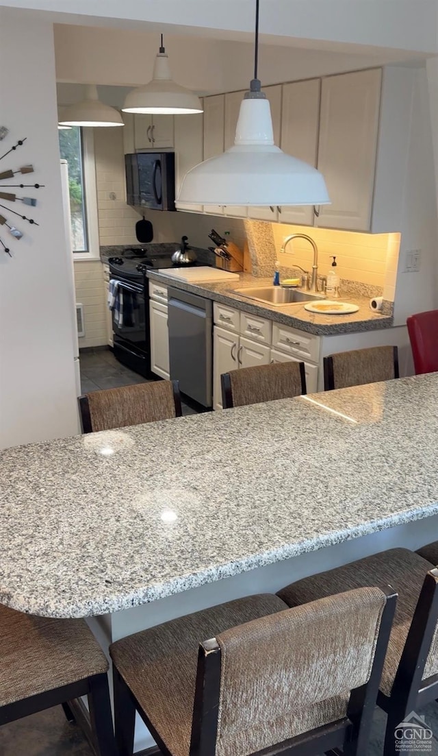 kitchen with pendant lighting, sink, a breakfast bar area, and black appliances