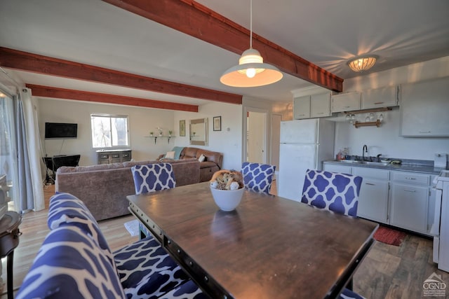 dining area featuring beamed ceiling, dark hardwood / wood-style floors, and sink