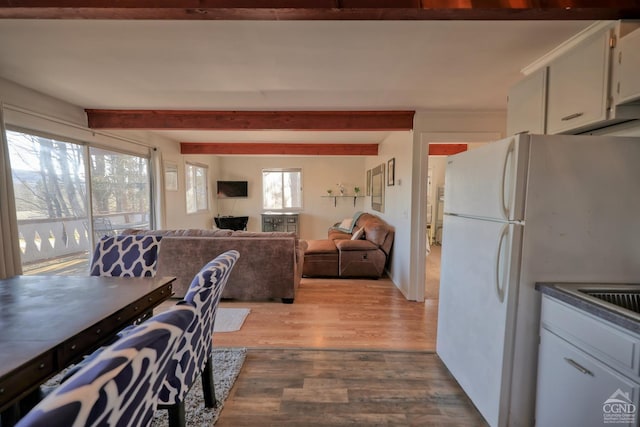 dining space with light hardwood / wood-style flooring and beamed ceiling