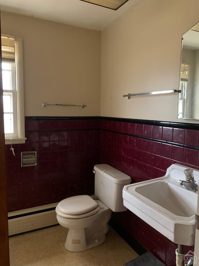 bathroom featuring baseboard heating, sink, and tile walls