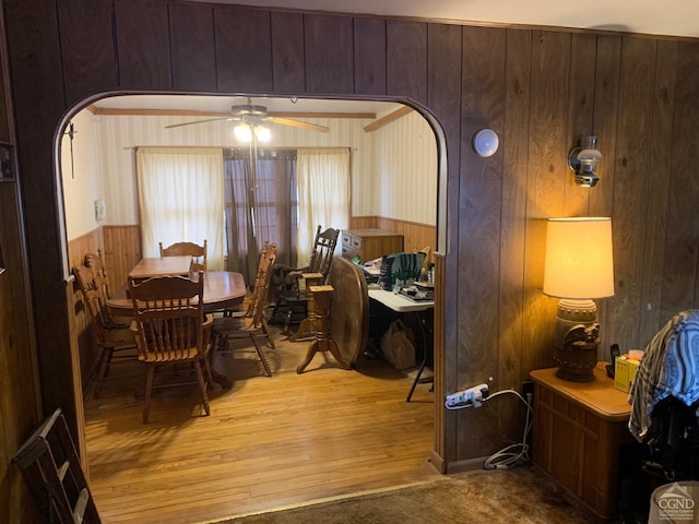 dining space featuring ceiling fan, wood walls, and light wood-type flooring