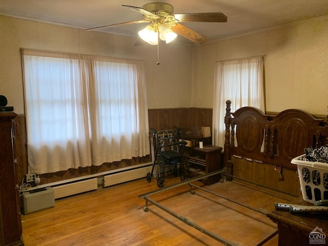 interior space with light hardwood / wood-style floors, ornamental molding, a baseboard radiator, and multiple windows