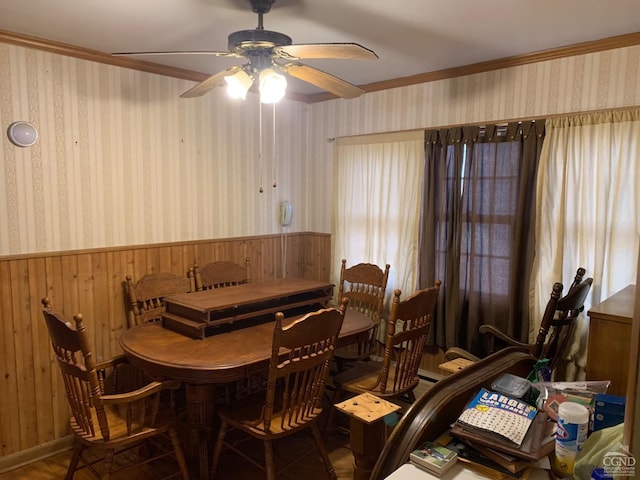 dining space with ceiling fan, wood walls, and crown molding