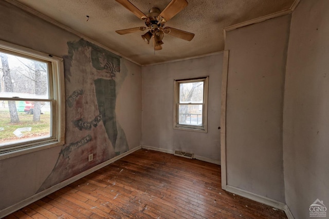 unfurnished room featuring a textured ceiling, ceiling fan, plenty of natural light, and dark wood-type flooring