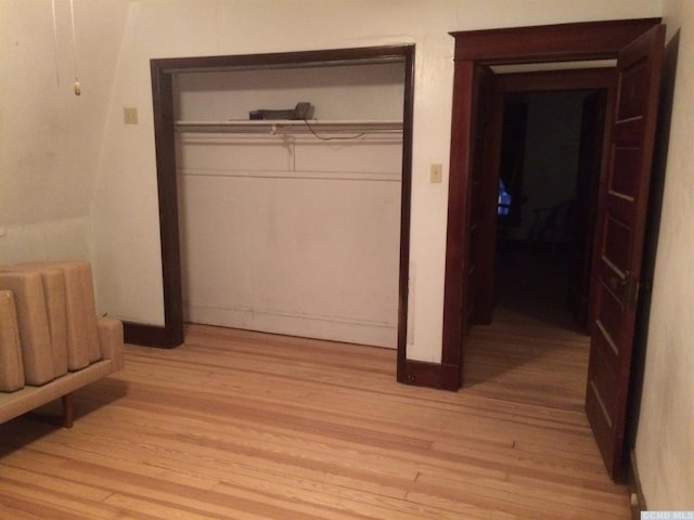 bedroom with a closet, light wood-style flooring, and baseboards