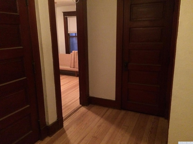 hallway with light wood-type flooring and baseboards