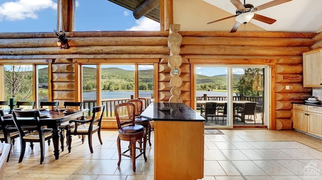 dining area featuring rustic walls, a mountain view, plenty of natural light, and ceiling fan