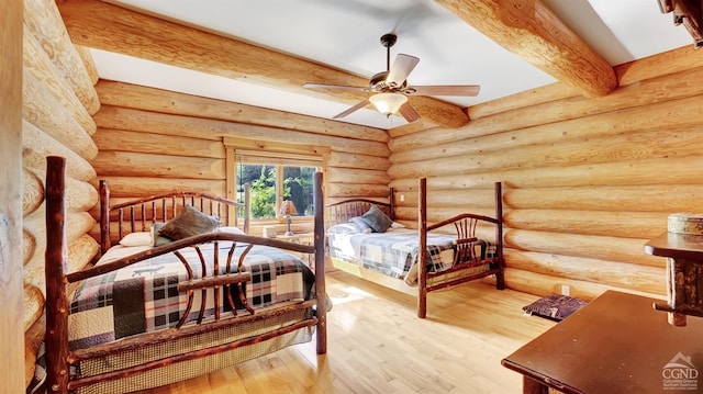 bedroom featuring beam ceiling, ceiling fan, log walls, and hardwood / wood-style flooring