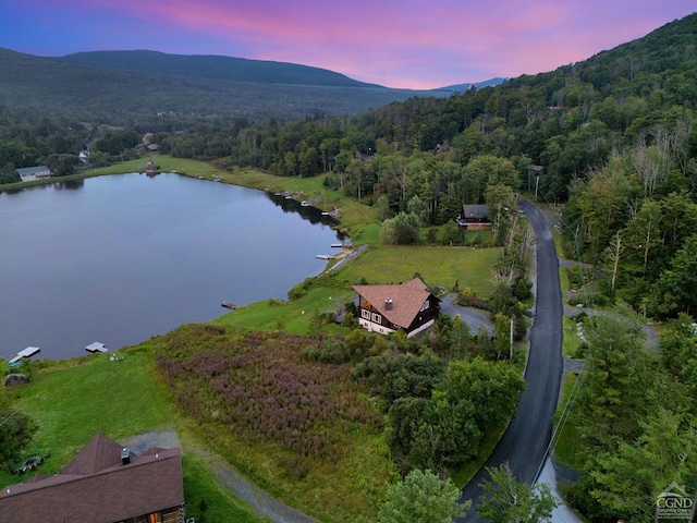 aerial view at dusk featuring a water and mountain view