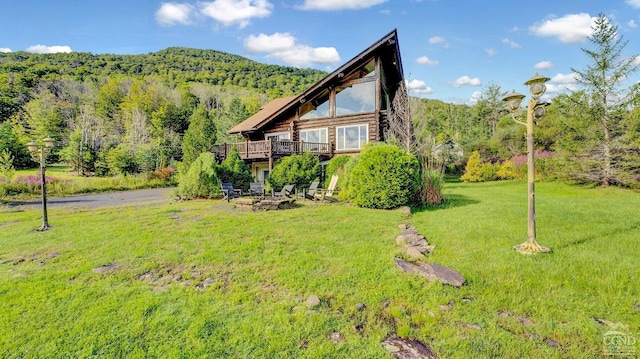 view of side of home featuring a deck with mountain view and a yard