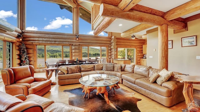 living room featuring log walls, beam ceiling, light wood-type flooring, and ceiling fan