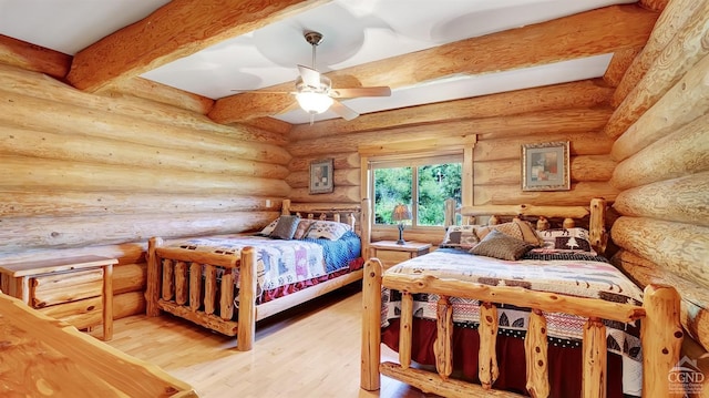 bedroom with beam ceiling, rustic walls, ceiling fan, and hardwood / wood-style floors