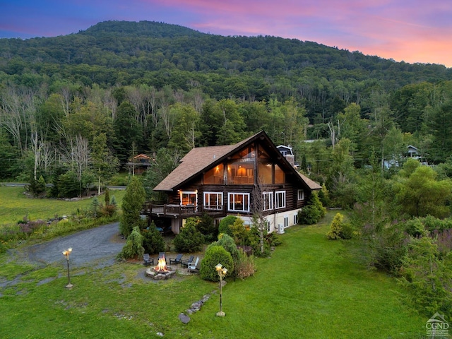 back house at dusk with a lawn and an outdoor fire pit