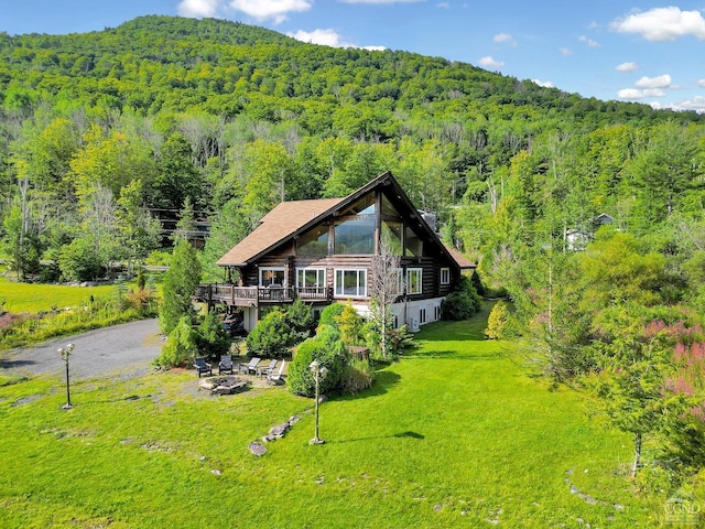 back of house featuring a yard, a fire pit, and a deck