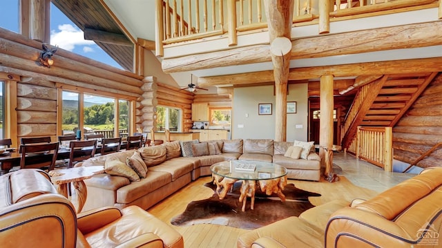 living room with a high ceiling, rustic walls, ceiling fan, and hardwood / wood-style floors