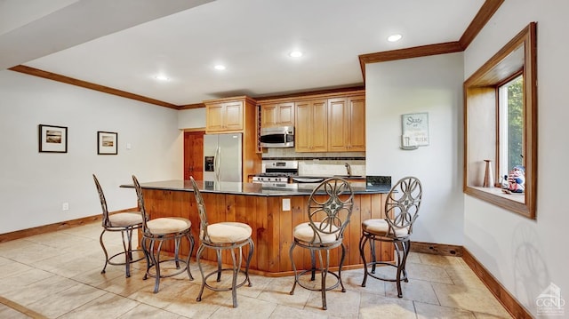 kitchen with a breakfast bar, backsplash, sink, ornamental molding, and stainless steel appliances