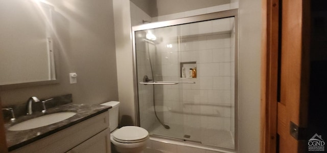 bathroom with walk in shower, vanity, and toilet