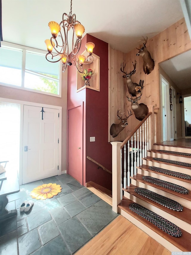 foyer with a notable chandelier, stone tile floors, and stairs