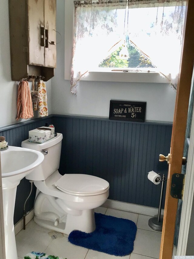 bathroom with wainscoting, wooden walls, toilet, and tile patterned floors