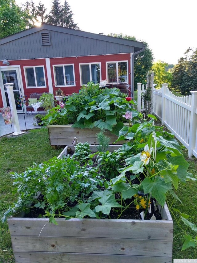 view of side of home with a yard, a patio area, fence, and a garden