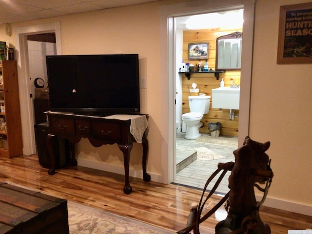 interior space with a paneled ceiling, baseboards, and wood finished floors