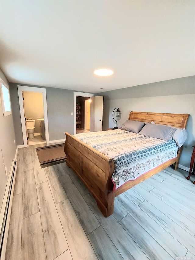 bedroom featuring ensuite bath, a baseboard radiator, baseboards, and wood finished floors