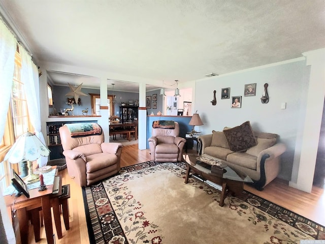 living room with ornamental molding, visible vents, and wood finished floors