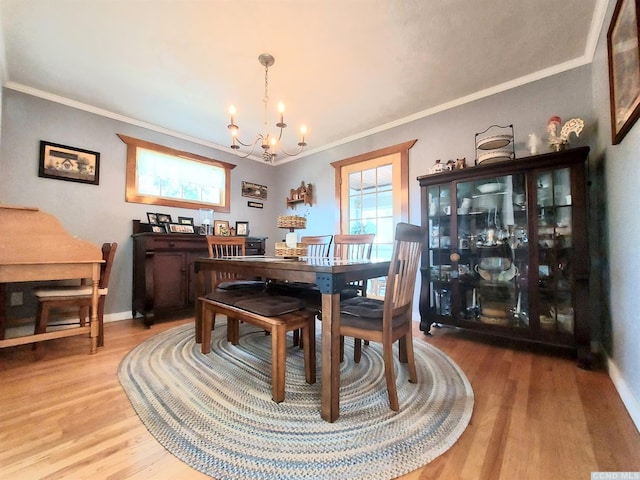 dining room featuring ornamental molding, light wood-style floors, baseboards, and a notable chandelier