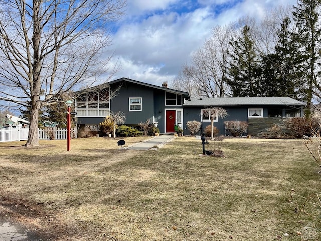 view of front of home featuring a chimney, a front yard, and fence