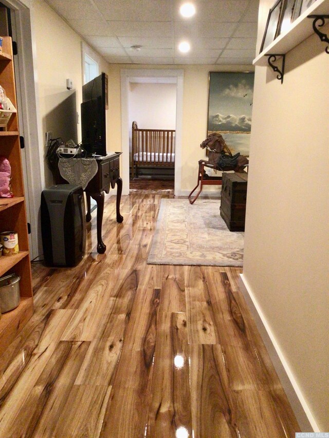 hallway featuring a drop ceiling, baseboards, and wood finished floors